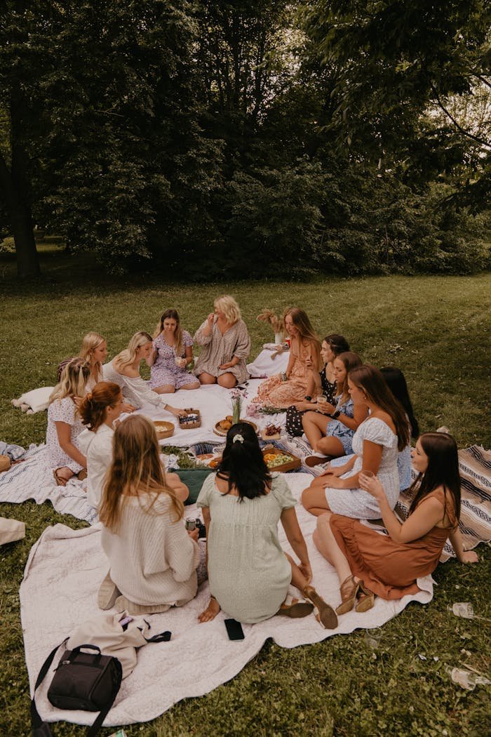 Group of women having a picnic in a park, enjoying food and leisure on a sunny day.